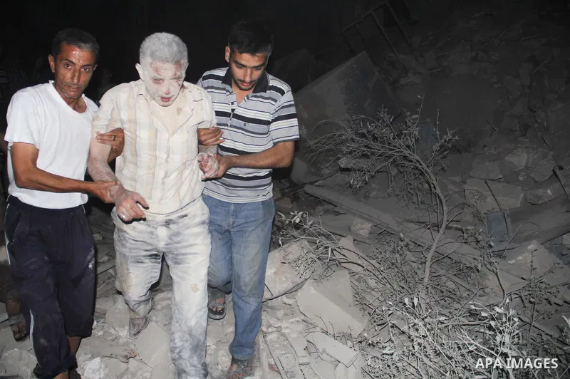 Syrians help an injured man following a reported bomb barrel attack by forces of Syria's President Bashar al-Assad at the old city of Aleppo, on August 2, 2015. At least 1 civilian killed 8 others were injured following...