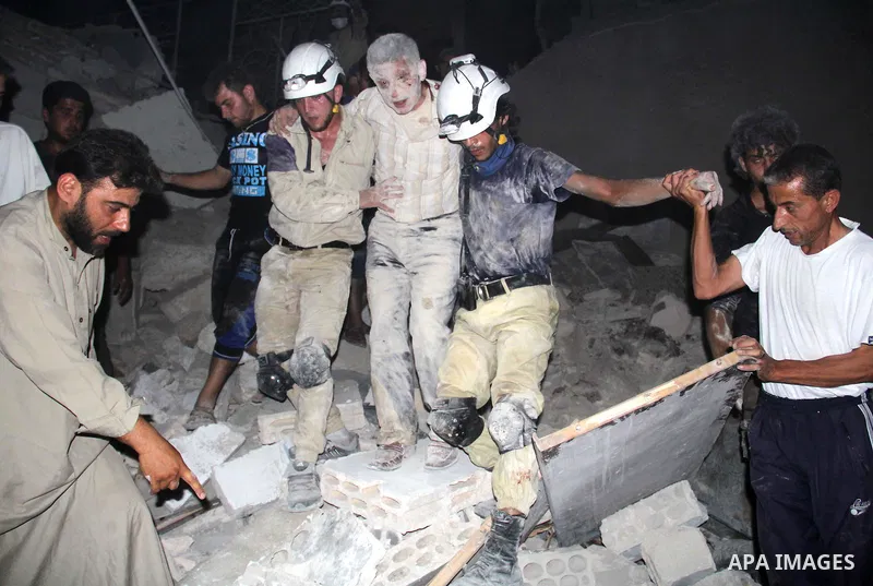 Syrian civil defence members help an injured man following a reported bomb barrel attack by forces of Syria's President Bashar al-Assad at the old city of Aleppo, on August 2, 2015. At least 1 civilian killed 8 others we...