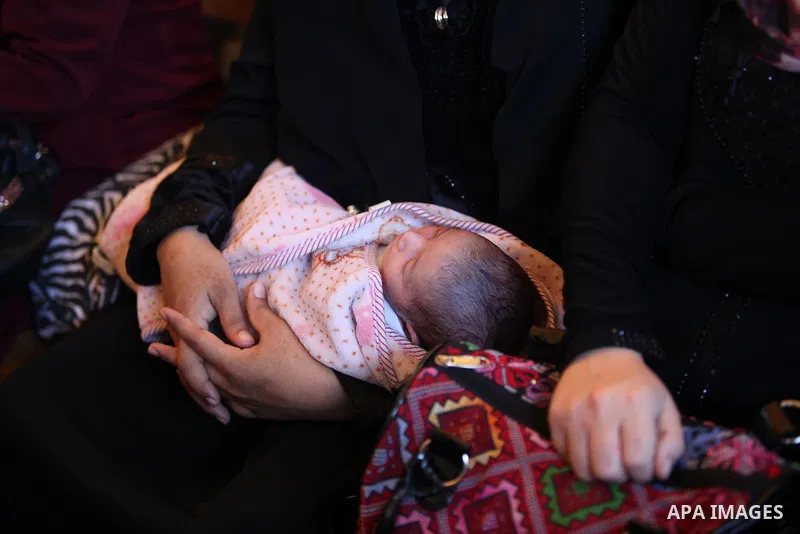 A Palestinian woman holds her child as she takes part in a protest demanding release the prisoners in Israeli jails, in front of Red cross office, in Gaza city, on on August 03, 2015. Photo by Ashraf Amra