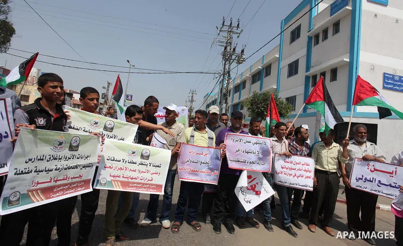 Palestinian students hold banners during a protest against the UNRWA decision to reduce of the aid and educational programs in Khan Younis in the southern Gaza strip on August 4, 2015. The United Nations Relief and Works...