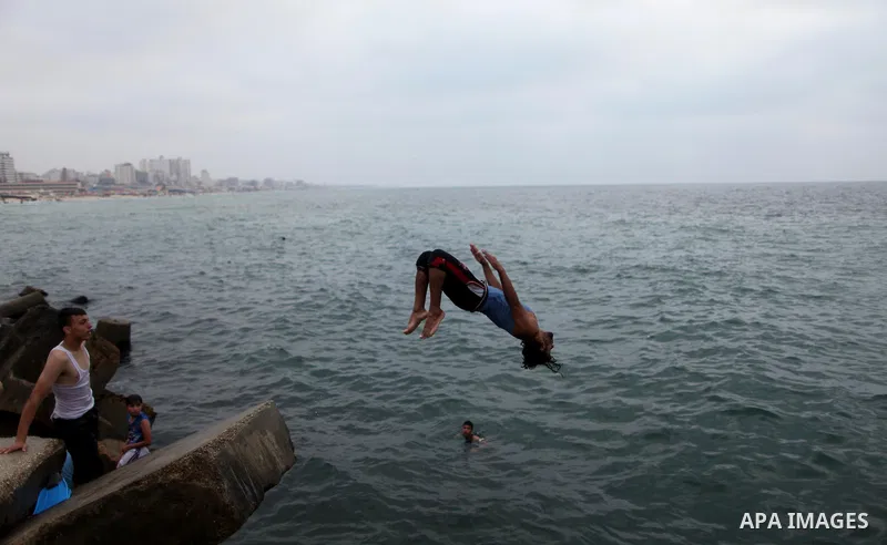 A Palestinian youth dives into the Mediterranean Sea on the coast of Gaza City on August 4, 2015. Across the Middle East, temperatures in the high 30’s Centigrade (upper 90’s Fahrenheit) and as high as 50 (122 Fahrenheit...