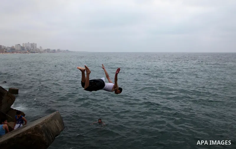 A Palestinian youth dives into the Mediterranean Sea on the coast of Gaza City on August 4, 2015. Across the Middle East, temperatures in the high 30’s Centigrade (upper 90’s Fahrenheit) and as high as 50 (122 Fahrenheit...