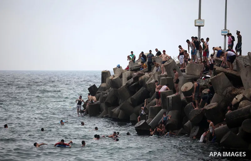 Palestinians swim into the Mediterranean Sea on the coast of Gaza City on August 4, 2015. Across the Middle East, temperatures in the high 30’s Centigrade (upper 90’s Fahrenheit) and as high as 50 (122 Fahrenheit) in som...