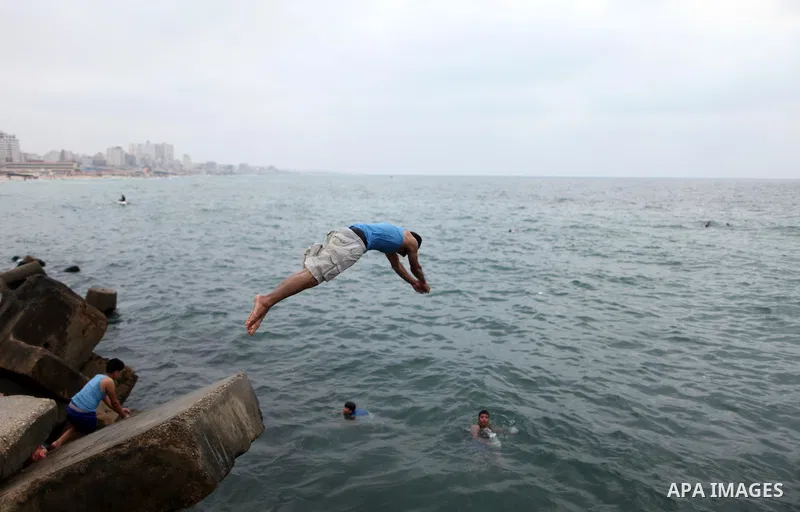 A Palestinian youth dives into the Mediterranean Sea on the coast of Gaza City on August 4, 2015. Across the Middle East, temperatures in the high 30’s Centigrade (upper 90’s Fahrenheit) and as high as 50 (122 Fahrenheit...