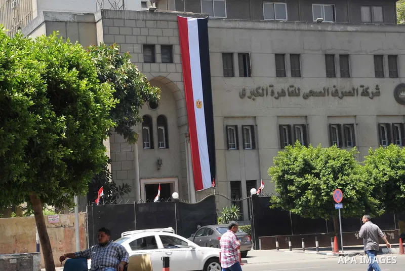 People walk past an Egyptian flag hanging on a building, in cairo, on August 5, 2015. Egypt on Thursday, Aug. 6, will unveil a major extension of the Suez Canal, a mega-project that has emerged as a cornerstone of Presid...