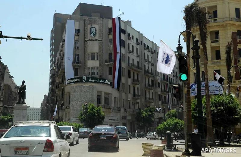 People walk past an Egyptian flag hanging on a building, in cairo, on August 5, 2015. Egypt on Thursday, Aug. 6, will unveil a major extension of the Suez Canal, a mega-project that has emerged as a cornerstone of Presid...