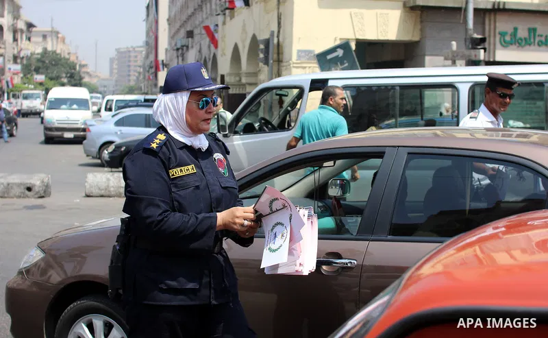 An Egyptian police officer distributes Egyptian and Suez flags in a street in cairo, on August 5, 2015. Egypt on Thursday, Aug. 6, will unveil a major extension of the Suez Canal, a mega-project that has emerged as a cor...