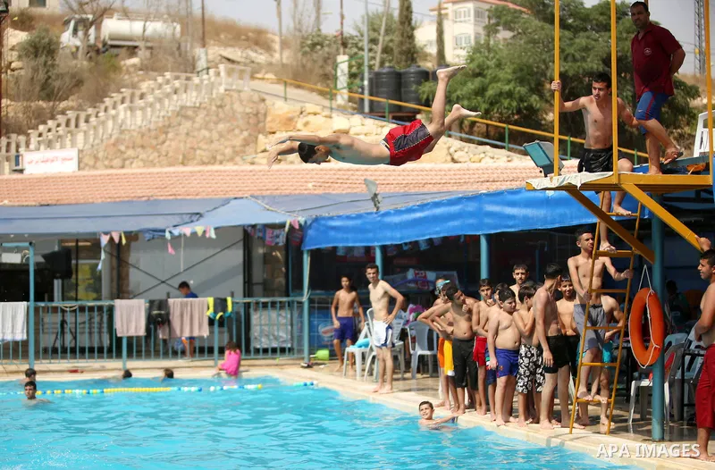 A Palestinian youth dives into a pool at a park in the West Bank city of Ramallah on August 5, 2015. Across the Middle East, temperatures in the high 30s Centigrade (upper 90s Fahrenheit) and as high as 50 (122 Fahrenhei...
