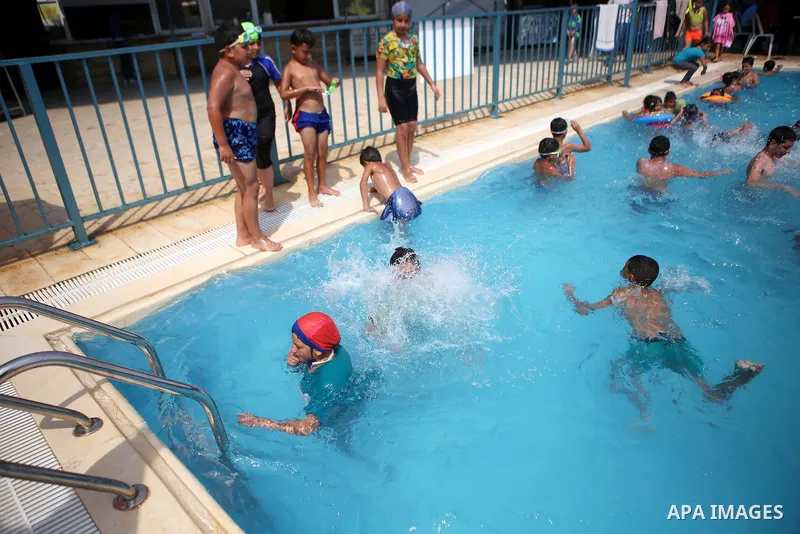 Palestinian youths enjoy swimming in a pool at a park in the West Bank city of Ramallah on August 5, 2015. Across the Middle East, temperatures in the high 30s Centigrade (upper 90s Fahrenheit) and as high as 50 (122 Fah...