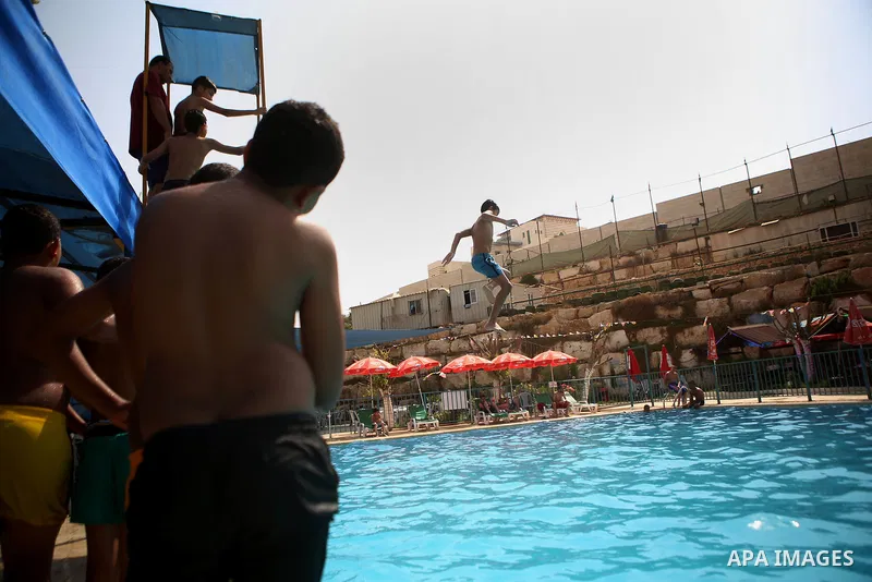 A Palestinian youth dives into a pool at a park in the West Bank city of Ramallah on August 5, 2015. Across the Middle East, temperatures in the high 30s Centigrade (upper 90s Fahrenheit) and as high as 50 (122 Fahrenhei...