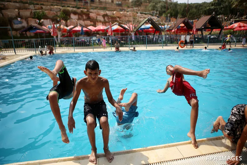 Palestinian youths dive into a pool at a park in the West Bank city of Ramallah on August 5, 2015. Across the Middle East, temperatures in the high 30s Centigrade (upper 90s Fahrenheit) and as high as 50 (122 Fahrenheit)...
