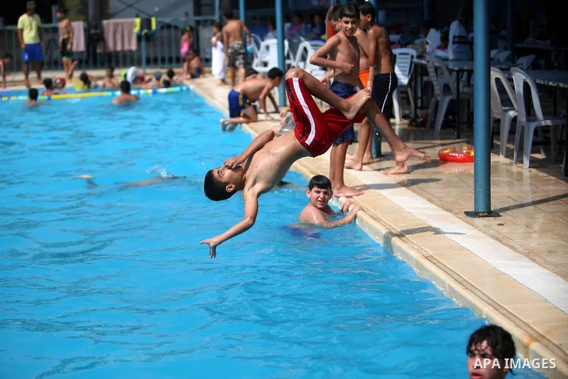 A Palestinian youth dives into a pool at a park in the West Bank city of Ramallah on August 5, 2015. Across the Middle East, temperatures in the high 30s Centigrade (upper 90s Fahrenheit) and as high as 50 (122 Fahrenhei...