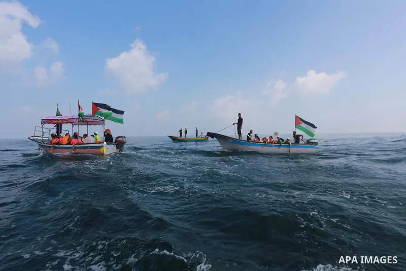 Palestinians riding boats hold Palestinian flags during a protest against the killing of 18-month-old Palestinian Ali Saad Dawabsheh, the toddler who was burned to death by suspected Jewish extremists, at the Seaport of...