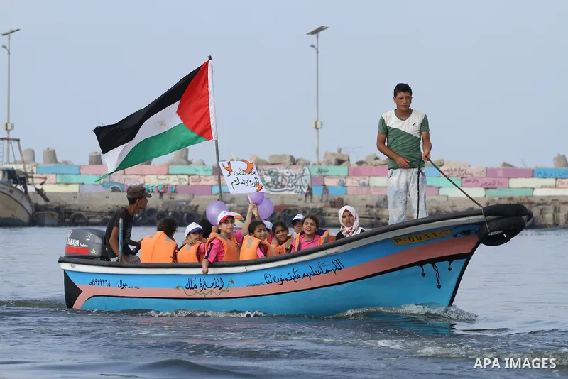 Palestinians riding boats hold Palestinian flags during a protest against the killing of 18-month-old Palestinian Ali Saad Dawabsheh, the toddler who was burned to death by suspected Jewish extremists, at the Seaport of...