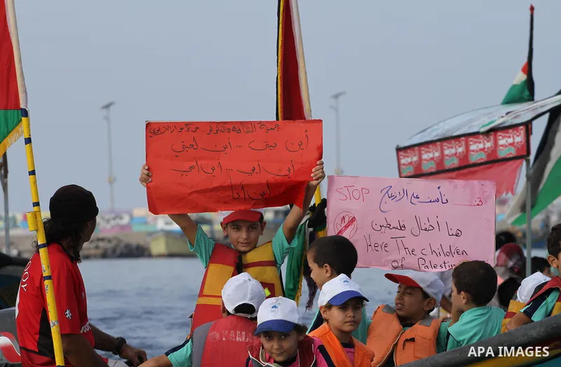Palestinians riding boats hold Palestinian flags during a protest against the killing of 18-month-old Palestinian Ali Saad Dawabsheh, the toddler who was burned to death by suspected Jewish extremists, at the Seaport of...