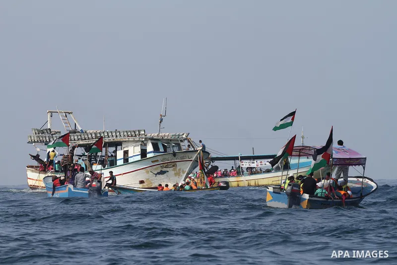 Palestinians riding boats hold Palestinian flags during a protest against the killing of 18-month-old Palestinian Ali Saad Dawabsheh, the toddler who was burned to death by suspected Jewish extremists, at the Seaport of...