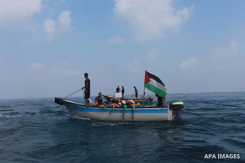 Palestinians riding boats hold Palestinian flags during a protest against the killing of 18-month-old Palestinian Ali Saad Dawabsheh, the toddler who was burned to death by suspected Jewish extremists, at the Seaport of...