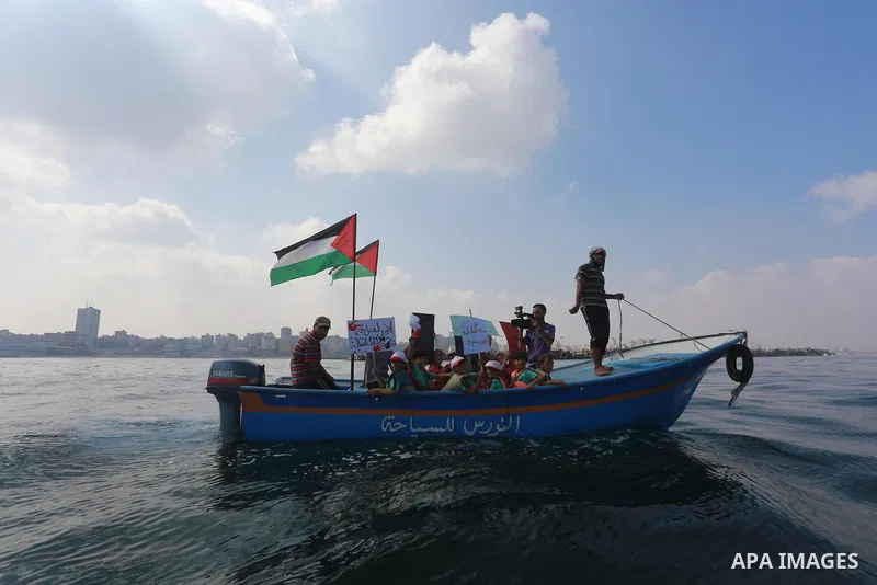 Palestinians riding boats hold Palestinian flags during a protest against the killing of 18-month-old Palestinian Ali Saad Dawabsheh, the toddler who was burned to death by suspected Jewish extremists, at the Seaport of...