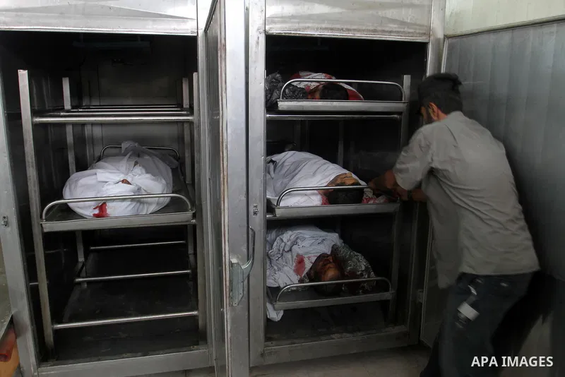 A Palestinian man stands next to four bodies lying at the morgue in the southern Gaza Strip town of Rafah following an explosion that ripped through a house in the nearby Al-Shabura refugee camp on August 6, 2015. The bl...