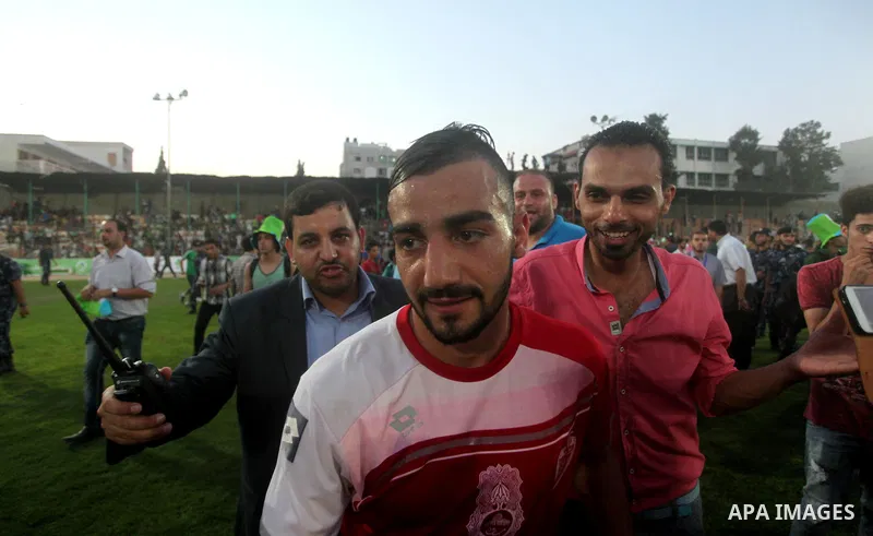 Palestinian player of Hebron's Al-Ahly team is surrounded by fans following the first leg match of the Palestine Cup final with Gaza's Shejaya team at Yarmuk stadium in Gaza City, on August 6, 2015, as the two teams play...