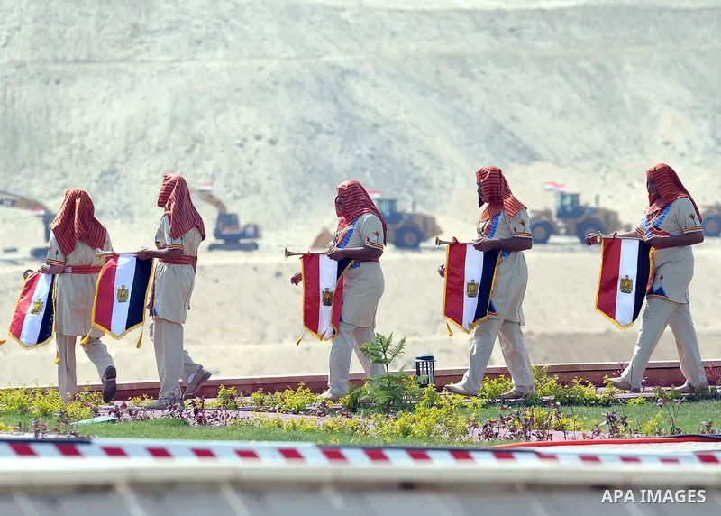 Egyptians wear Pharaonic costumes as they march in front of a statue representing a man digging during the inauguration ceremony of the new Suez Canal, in Ismailia, Egypt, August 6, 2015. Egypt staged a show of internati...
