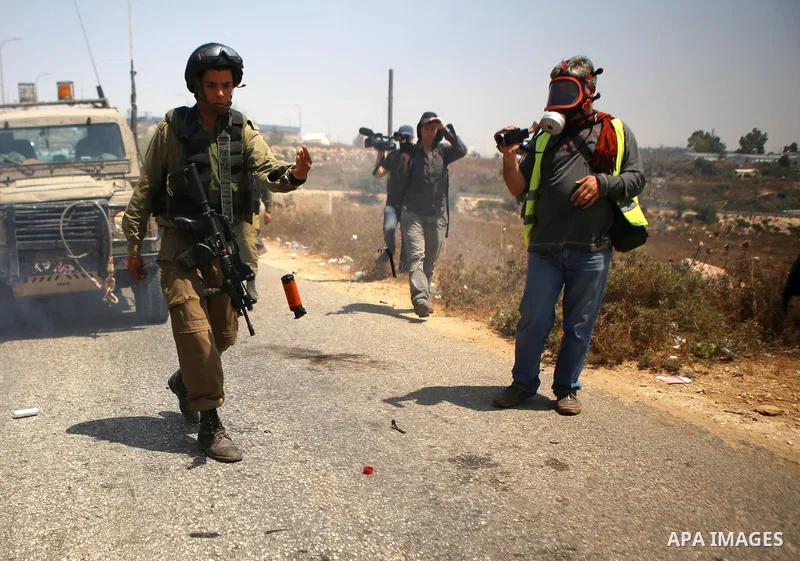 A Member of Israeli security forces hurl a tear gas canister with Palestinian protesters following a protest against Jewish settlements and the expropriation of Palestinian land in the West Bank village of Nabi Saleh, ne...