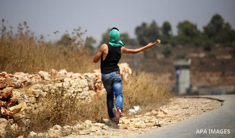 A Palestinian protester uses a sling to hurl stones at Israeli troops during clashes following a protest against Jewish settlements and the expropriation of Palestinian land in the West Bank village of Nabi Saleh, near R...