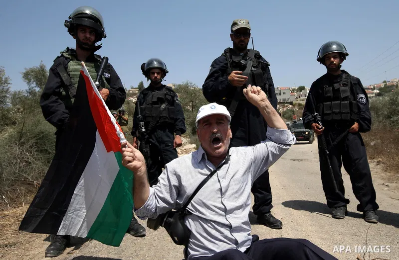 A Palestinian protester waves his national flag during clashes with Israeli security forces following a protest against the expropriation of Palestinian land by Israel in the West Bank village of Kafr Qaddum, near the no...