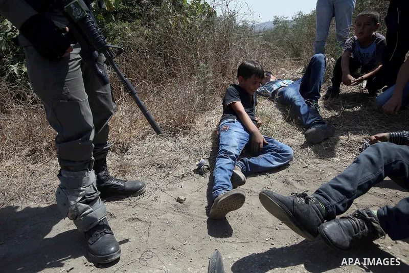 Palestinian boys sit on the land during clashes with Israeli security forces following a protest against the expropriation of Palestinian land by Israel in the West Bank village of Kafr Qaddum, near the northern city of...