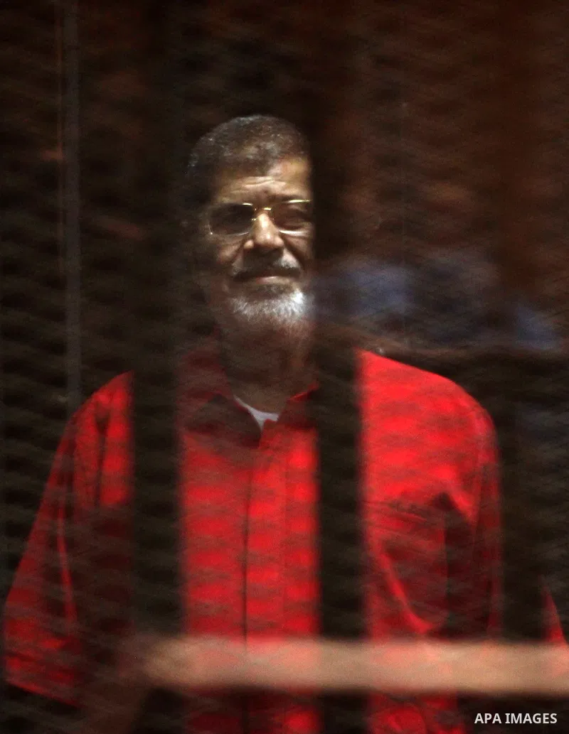 Ousted Egyptian president Mohammed Morsi stands behind bars during his trail in a court in Cairo on August 8, 2015. Cairo Criminal Court resumes on Saturday the trial of former Islamist president Mohamed Morsi and ten ot...