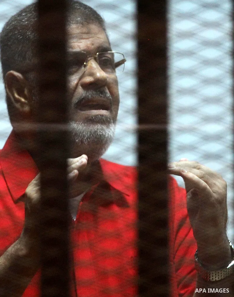 Ousted Egyptian president Mohammed Morsi speaks to judge as he stands behind bars during his trail in a court in Cairo on August 8, 2015. Cairo Criminal Court resumes on Saturday the trial of former Islamist president Mo...