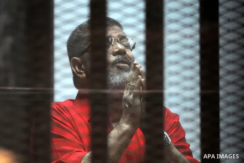 Ousted Egyptian president Mohammed Morsi speaks to judge as he stands behind bars during his trail in a court in Cairo on August 8, 2015. Cairo Criminal Court resumes on Saturday the trial of former Islamist president Mo...