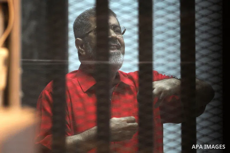 Ousted Egyptian president Mohammed Morsi speaks to judge as he stands behind bars during his trail in a court in Cairo on August 8, 2015. Cairo Criminal Court resumes on Saturday the trial of former Islamist president Mo...