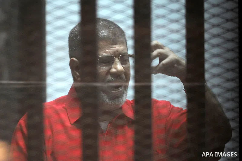 Ousted Egyptian president Mohammed Morsi speaks to judge as he stands behind bars during his trail in a court in Cairo on August 8, 2015. Cairo Criminal Court resumes on Saturday the trial of former Islamist president Mo...