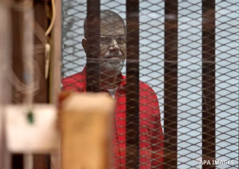 Ousted Egyptian president Mohammed Morsi stands behind bars during his trail in a court in Cairo on August 8, 2015. Cairo Criminal Court resumes on Saturday the trial of former Islamist president Mohamed Morsi and ten ot...