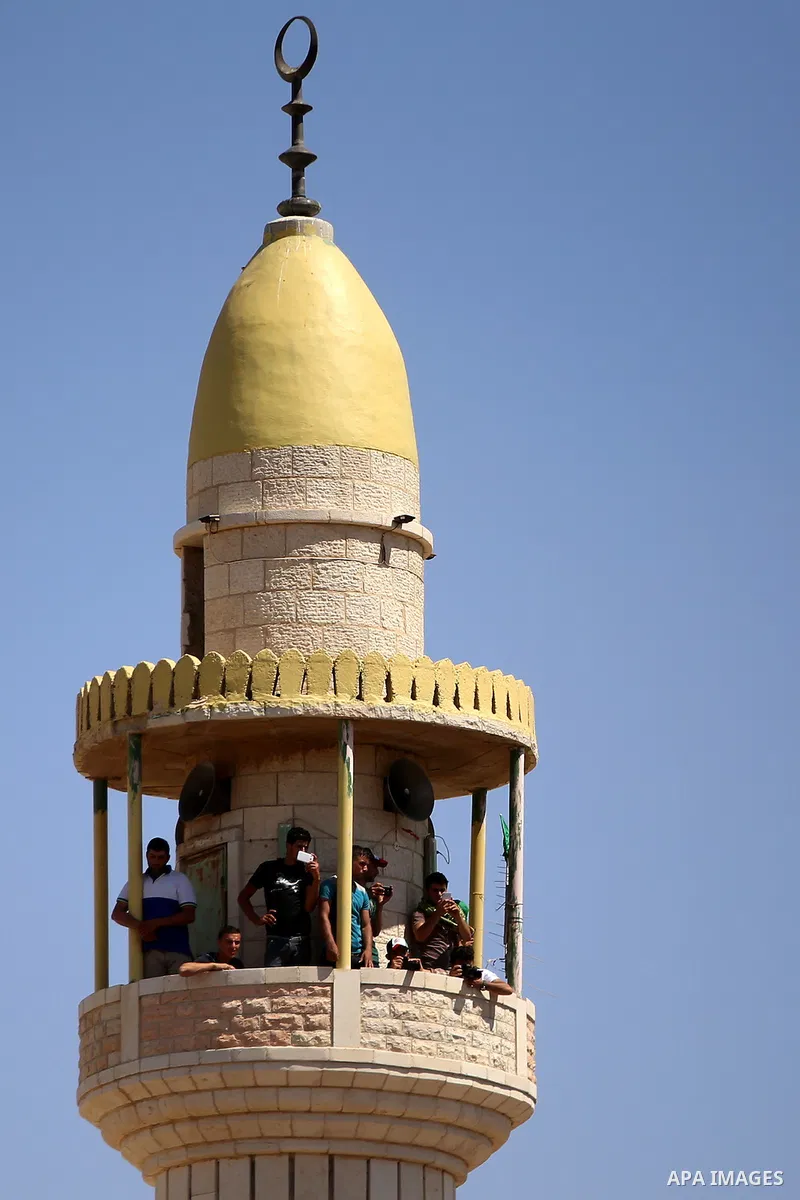 Palestinians stand on the minaret of a mosque during the funeral of Saad Dawabsha, the father of a Palestinian toddler killed last week when their home was firebombed by Jewish extremists, in the West Bank village of Dum...