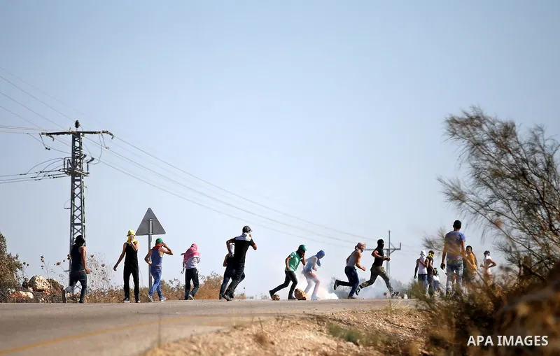 Palestinian protesters throw stones towards Israeli security forces during clashes on a street leading to Duma village, in a demonstration following the funeral of Saad Dawabsha, the father of a Palestinian toddler kille...