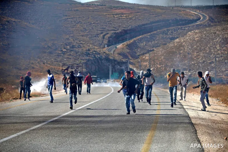 Palestinian protesters throw stones towards Israeli security forces during clashes on a street leading to Duma village, in a demonstration following the funeral of Saad Dawabsha, the father of a Palestinian toddler kille...