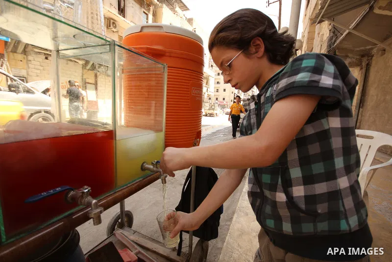 Fouad, a 11-year-old Syrian boy, sells juice in a street in a rebel-controlled area of Aleppo, on August 8, 2015. Fouad works everyday following the school time to provide for his small family, as his father suffers from...