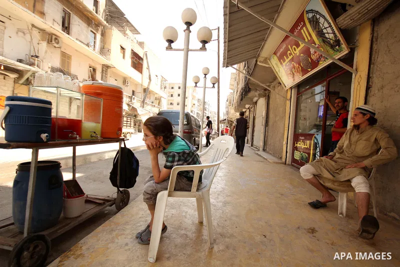 Fouad, a 11-year-old Syrian boy, sits next to his juice cart, in a street in a rebel-controlled area of Aleppo, on August 8, 2015. Fouad works everyday following the school time to provide for his small family, as his fa...