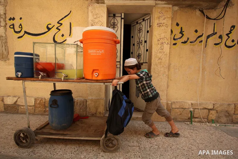 Fouad, a 11-year-old Syrian boy, pushes his juice cart, in a street in a rebel-controlled area of Aleppo, on August 8, 2015. Fouad works everyday following the school time to provide for his small family, as his father s...