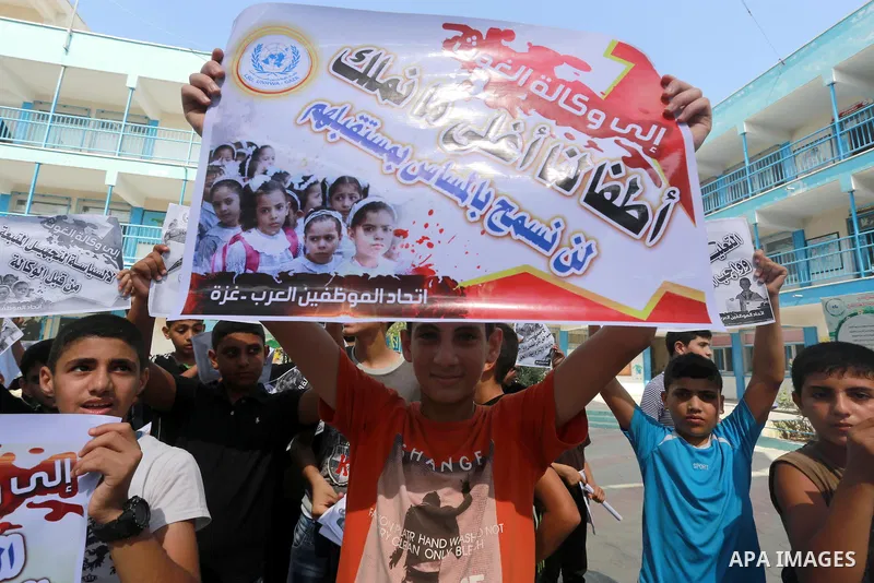 Palestinian children hold banners during a protest against the reduction of educational programs given by United Nations Relief and Works Agency (UNRWA) in Jabalia in the northern of Gaza strip on August 9, 2015. The UNR...