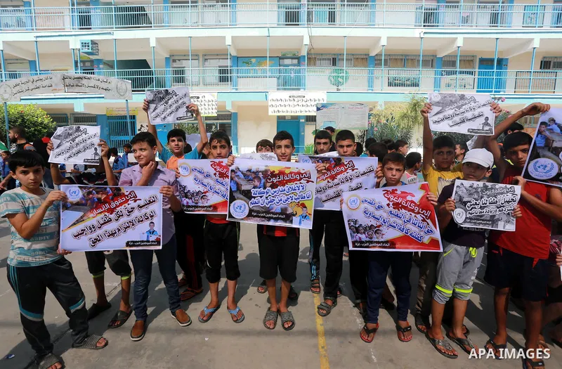 Palestinian children hold banners during a protest against the reduction of educational programs given by United Nations Relief and Works Agency (UNRWA) in Jabalia in the northern of Gaza strip on August 9, 2015. The UNR...