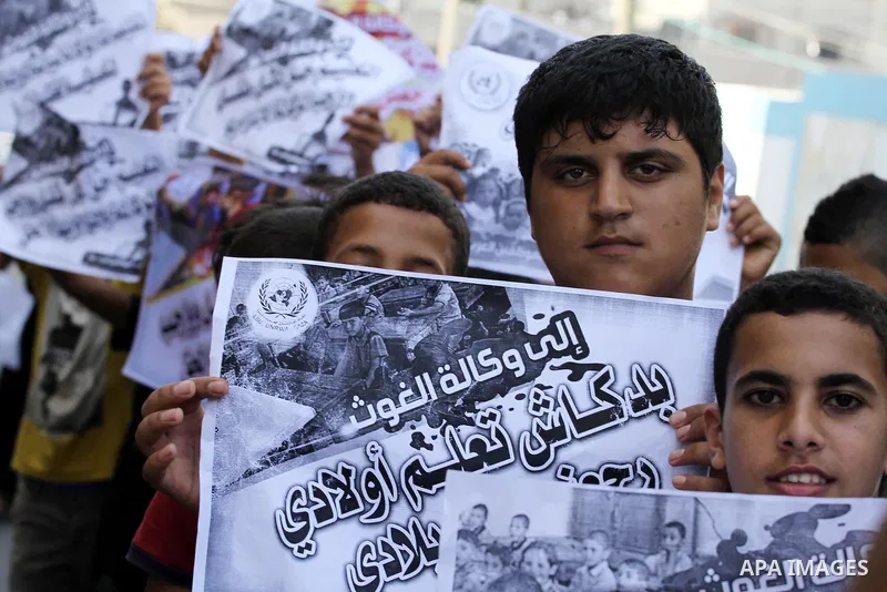 Palestinian children hold banners during a protest against the reduction of educational programs given by United Nations Relief and Works Agency (UNRWA) in Jabalia in the northern of Gaza strip on August 9, 2015. The UNR...