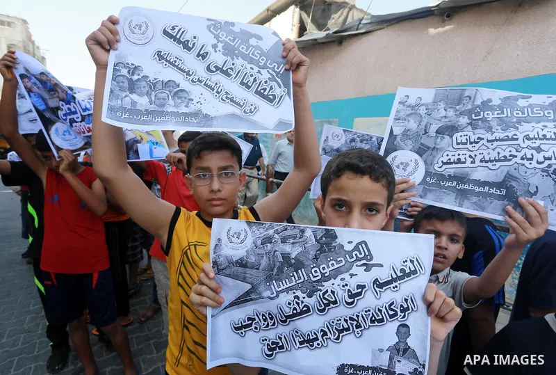 Palestinian children hold banners during a protest against the reduction of educational programs given by United Nations Relief and Works Agency (UNRWA) in Jabalia in the northern of Gaza strip on August 9, 2015. The UNR...