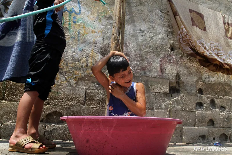 Palestinian children enjoy themselves with water during a sweltering heat wave, in Rafah in the southern Gaza strip, on August 9, 2015. Photo by Abed Rahim Khatib