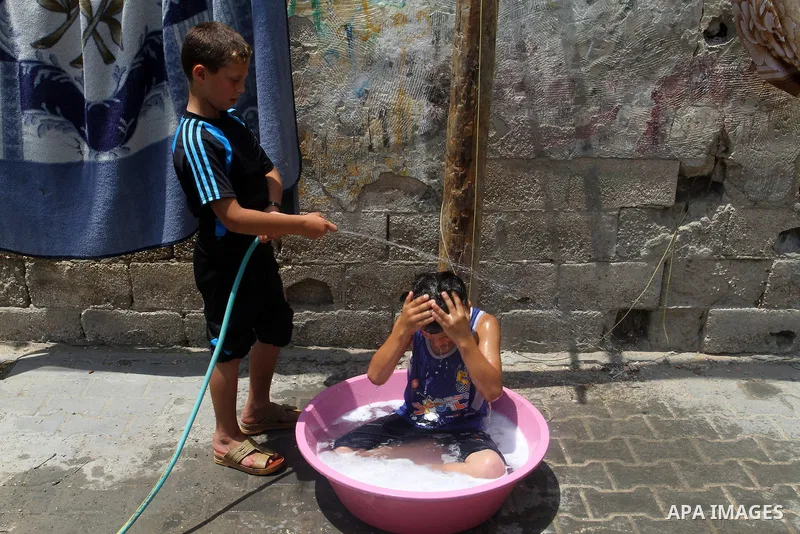 Palestinian children enjoy themselves with water during a sweltering heat wave, in Rafah in the southern Gaza strip, on August 9, 2015. Photo by Abed Rahim Khatib