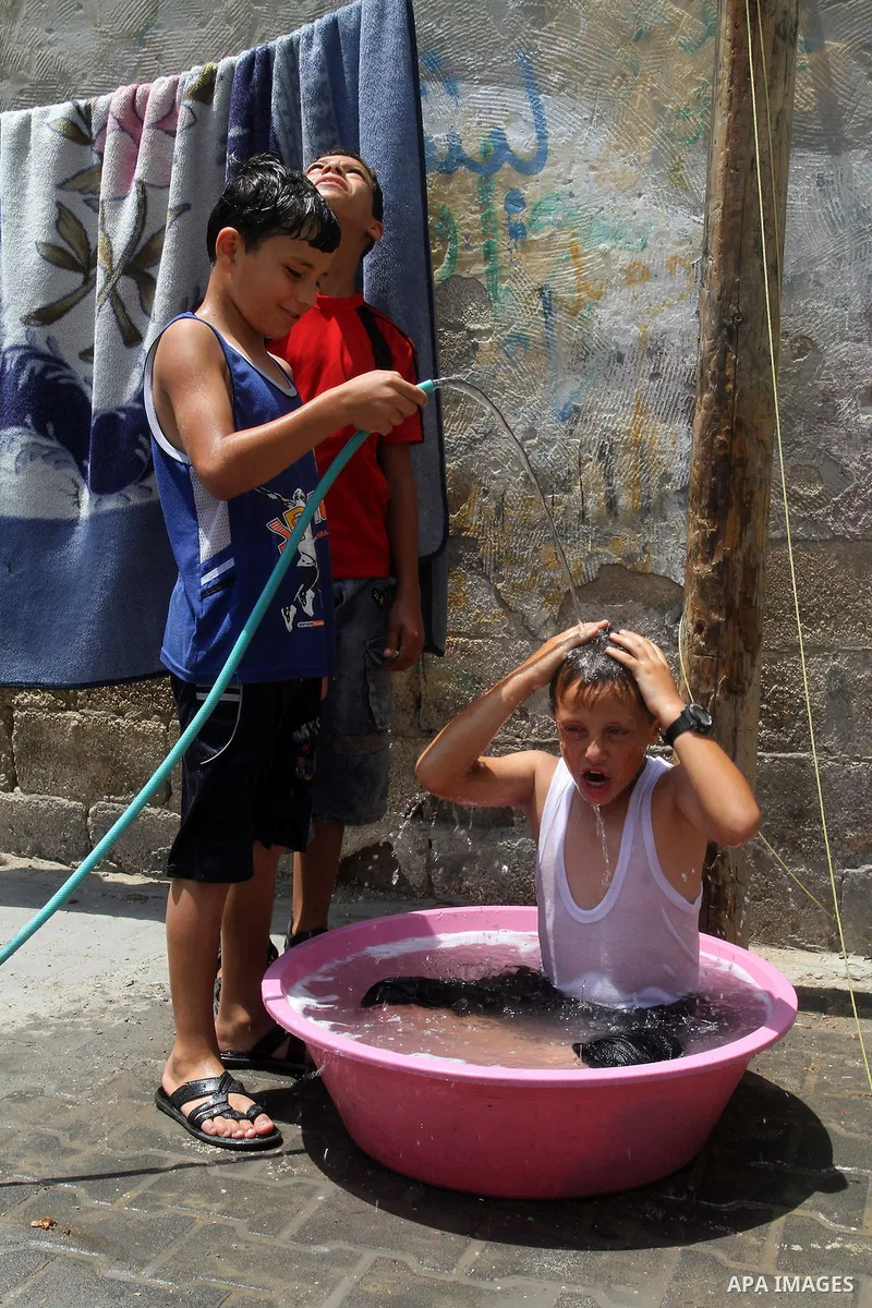 Palestinian children enjoy themselves with water during a sweltering heat wave, in Rafah in the southern Gaza strip, on August 9, 2015. Photo by Abed Rahim Khatib