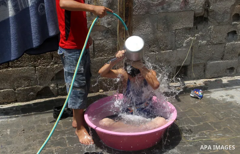 Palestinian children enjoy themselves with water during a sweltering heat wave, in Rafah in the southern Gaza strip, on August 9, 2015. Photo by Abed Rahim Khatib