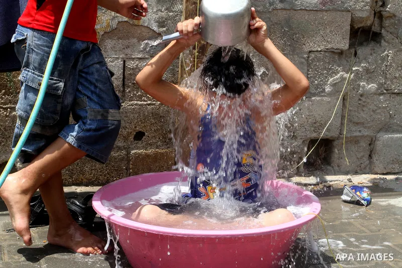 Palestinian children enjoy themselves with water during a sweltering heat wave, in Rafah in the southern Gaza strip, on August 9, 2015. Photo by Abed Rahim Khatib